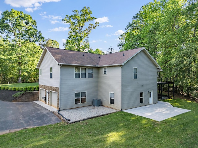 rear view of property featuring a garage, central AC unit, a patio area, and a yard