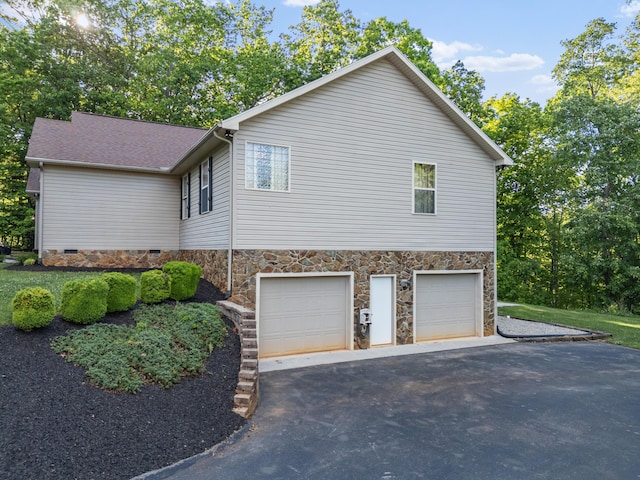 view of property exterior featuring asphalt driveway, an attached garage, and stone siding