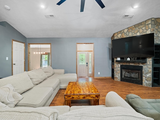 living room with lofted ceiling, ceiling fan, wood finished floors, plenty of natural light, and a textured ceiling