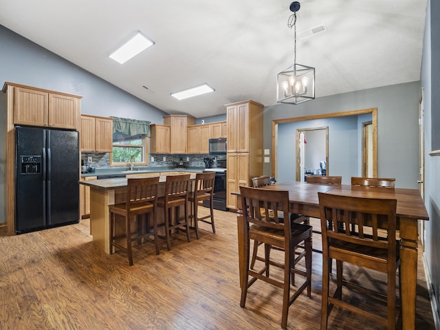 dining room with vaulted ceiling, light wood-type flooring, and a chandelier