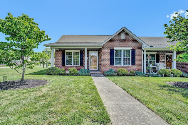 view of front of home with a front lawn, covered porch, brick siding, and a shingled roof
