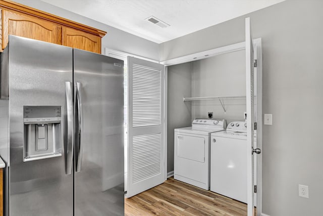 laundry room featuring independent washer and dryer, light wood-style floors, and baseboards