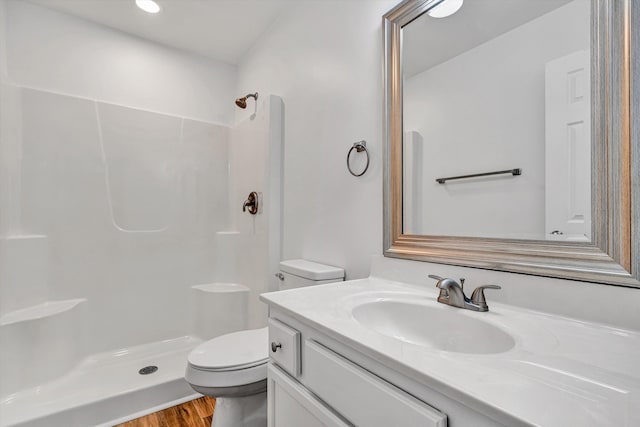 bathroom with a shower, toilet, vanity, and wood finished floors