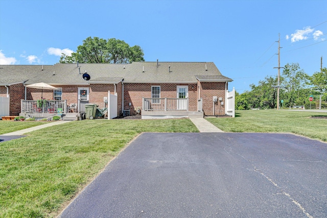 rear view of property featuring brick siding, a yard, and a shingled roof