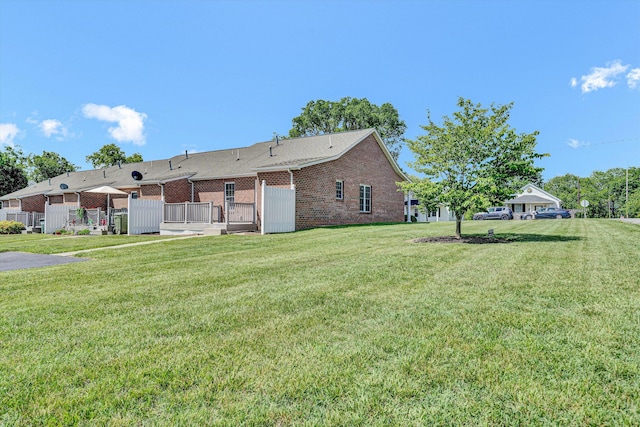 rear view of house with brick siding and a yard