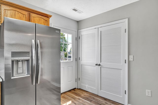 kitchen featuring stainless steel refrigerator with ice dispenser, light wood-style flooring, and brown cabinetry