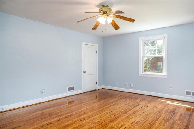 empty room featuring wood finished floors, baseboards, and a ceiling fan