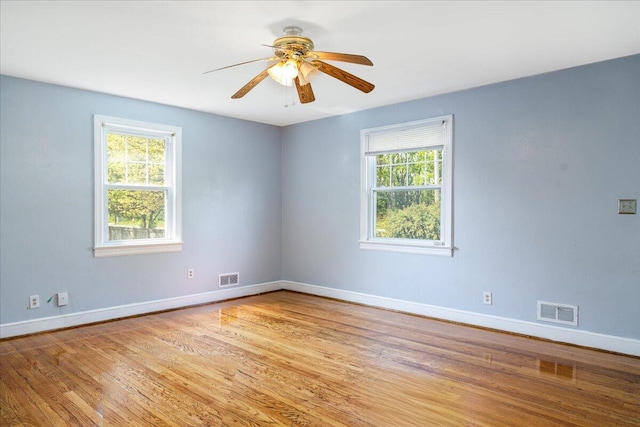 empty room featuring plenty of natural light, baseboards, light wood-type flooring, and ceiling fan