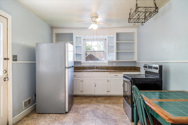 kitchen with freestanding refrigerator, electric range oven, a sink, a ceiling fan, and white cabinets