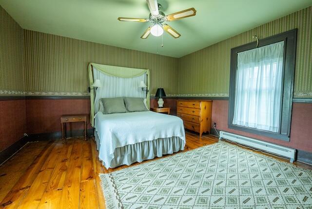 336 Turkey Run Ln, Rural Retreat, VA 24368 - bedroom with a baseboard radiator, wallpapered walls, wood finished floors, and a ceiling fan