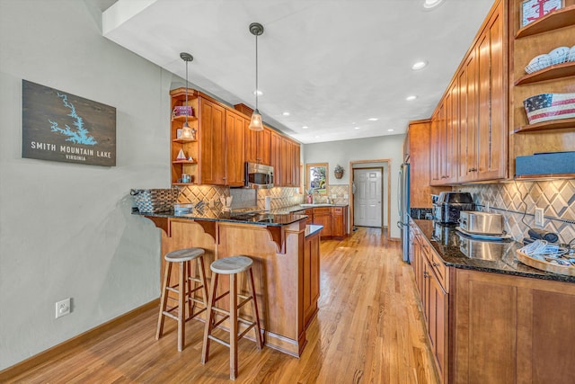 kitchen featuring open shelves, appliances with stainless steel finishes, brown cabinets, a peninsula, and light wood-style floors