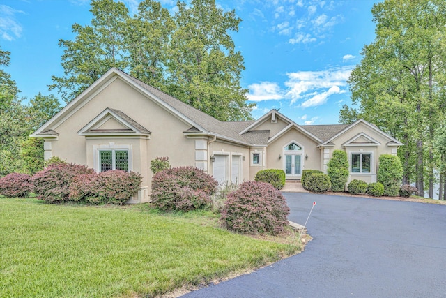 single story home featuring asphalt driveway, stucco siding, a garage, a front lawn, and french doors