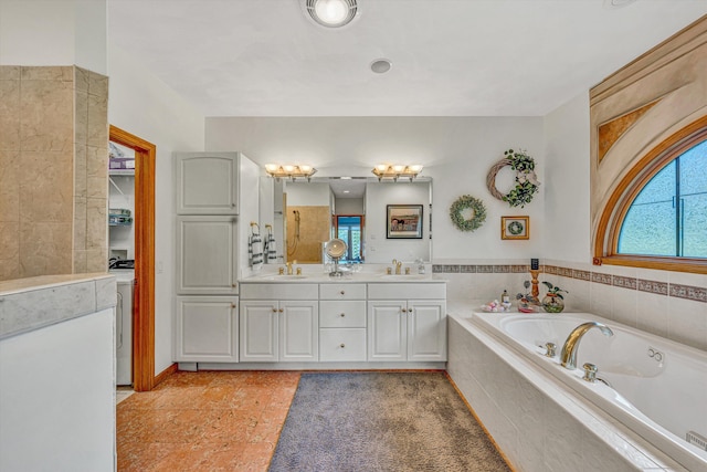 bathroom featuring healthy amount of natural light, a bath, double vanity, and washer / dryer