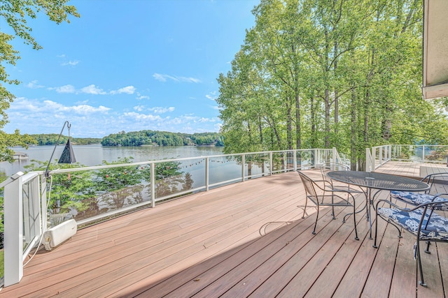 deck with a water view and outdoor dining area