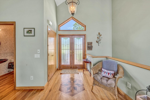 entryway with baseboards, a towering ceiling, french doors, and wood finished floors