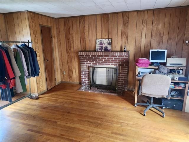 home office with a fireplace, wood finished floors, and wood walls