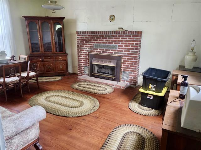 living room with wood finished floors and a brick fireplace