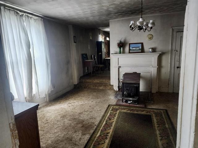 living area featuring a wood stove, a chandelier, and carpet