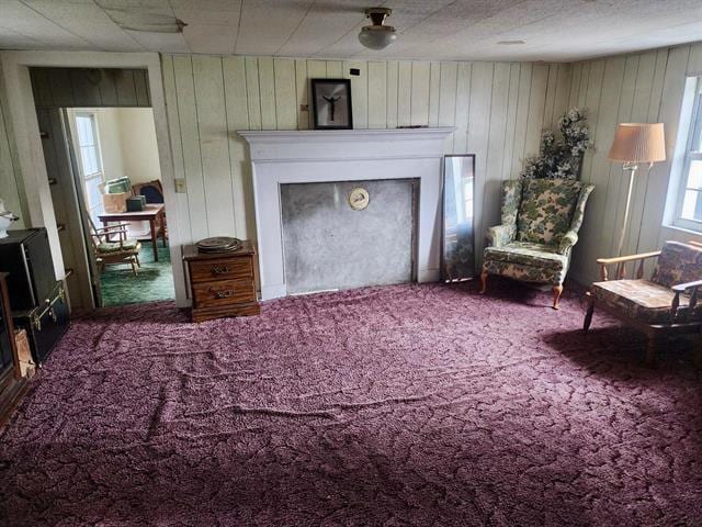 sitting room featuring carpet, a fireplace, and wooden walls