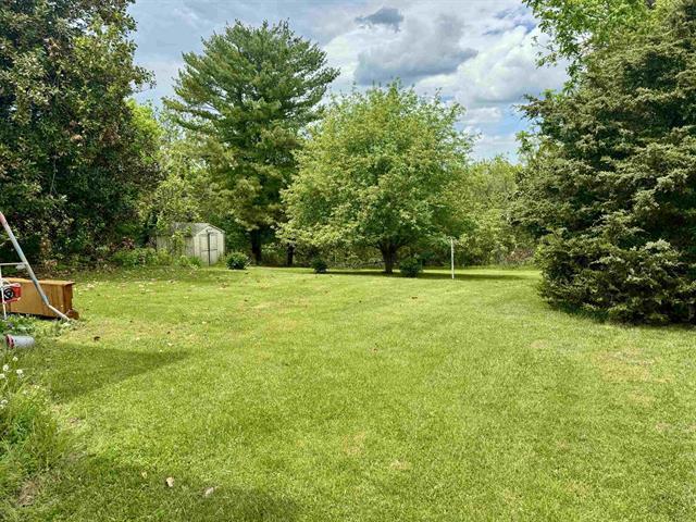 view of green lawn featuring a storage shed and an outbuilding