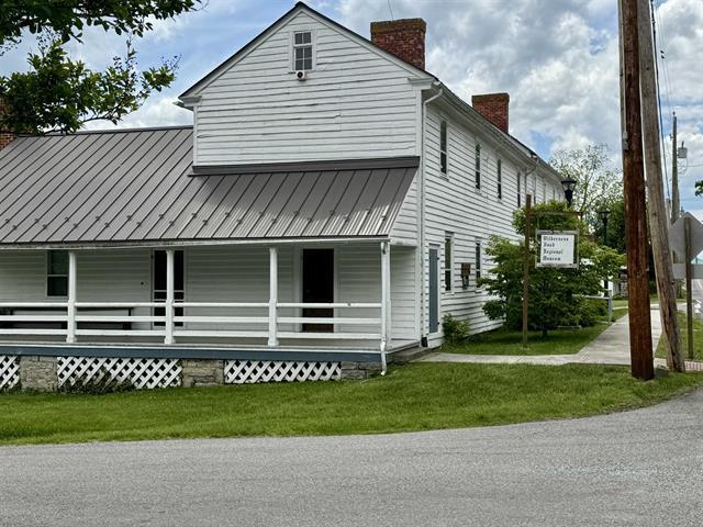 view of side of property with a chimney, a porch, metal roof, and a yard