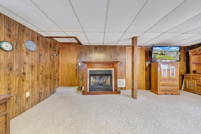 1921 Clinton Ave SE, Roanoke, VA 24013 - unfurnished living room with wooden walls, carpet flooring, a fireplace with raised hearth, and a paneled ceiling