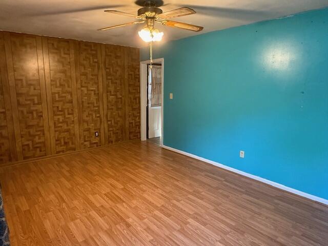 1433 Morehead Ave SE, Roanoke, VA 24013 - spare room featuring ceiling fan, wood finished floors, baseboards, and wood walls