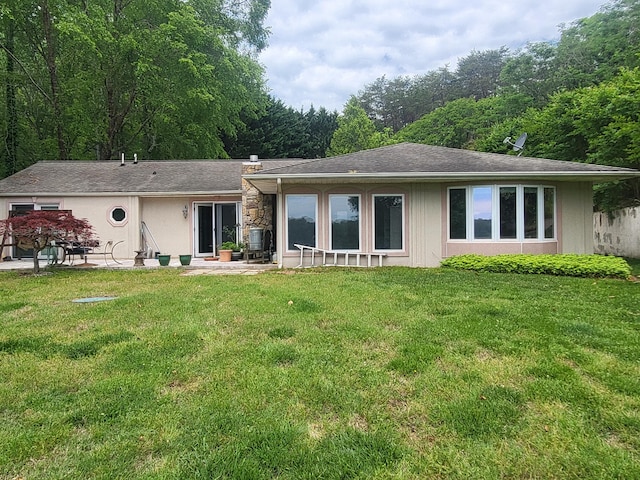 back of house featuring a lawn, a patio area, and roof with shingles