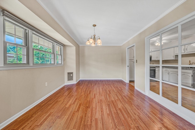spare room featuring a chandelier, light wood-style floors, crown molding, baseboards, and ceiling fan