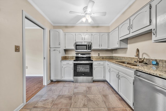 kitchen with appliances with stainless steel finishes, a sink, a ceiling fan, light stone counters, and crown molding