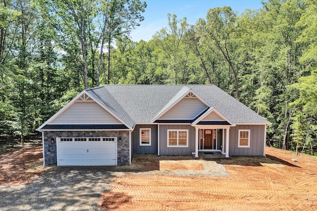 342 Morgans Mill Dr, Penhook, VA 24137 - view of front facade featuring driveway, a garage, a wooded view, stone siding, and a shingled roof