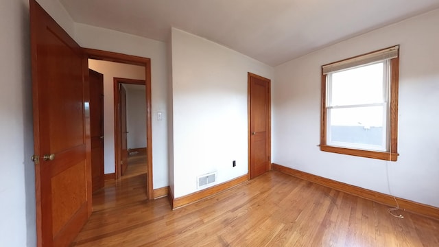 spare room with baseboards and light wood-style floors