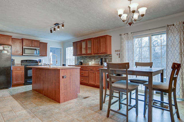 1944 Dickerson Mill Rd, Bedford, VA 24523 - kitchen with black appliances, brown cabinetry, ornamental molding, plenty of natural light, and a kitchen island with sink