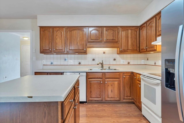 2420 Carlsbad Cir, Roanoke, VA 24012 - kitchen featuring a sink, white appliances, under cabinet range hood, brown cabinetry, and tasteful backsplash