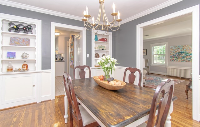 dining room featuring radiator heating unit, a chandelier, wood finished floors, crown molding, and built in shelves