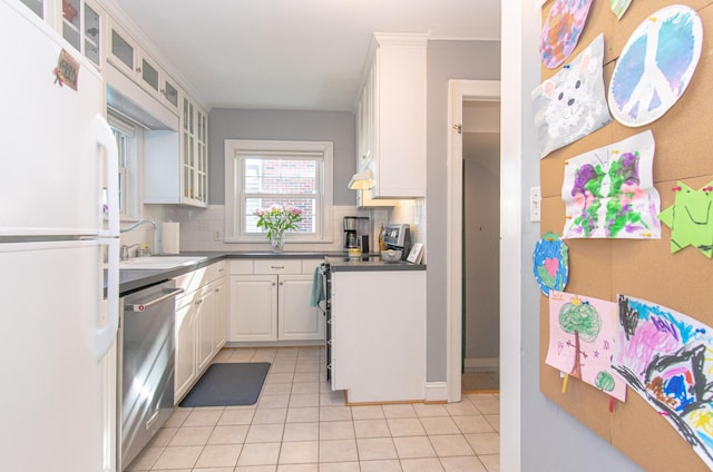kitchen featuring freestanding refrigerator, a sink, dishwasher, tasteful backsplash, and light tile patterned flooring