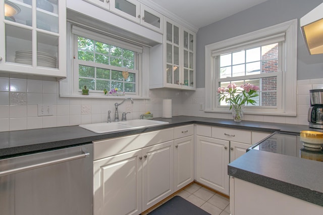 kitchen with dishwasher, a sink, dark countertops, and healthy amount of natural light