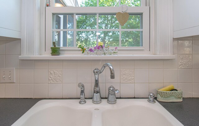 kitchen view of a sink, white cabinetry, and decorative backsplash
