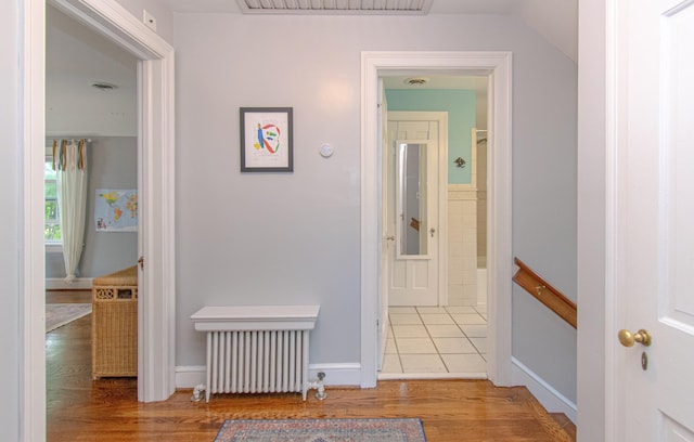 hall featuring radiator, wood finished floors, lofted ceiling, and baseboards