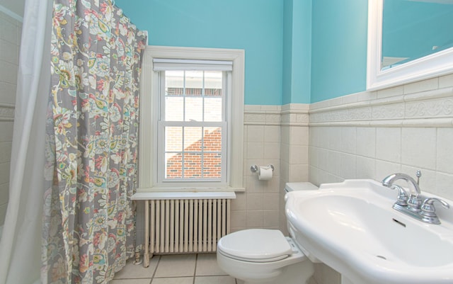bathroom with radiator heating unit, a sink, tile walls, tile patterned floors, and toilet