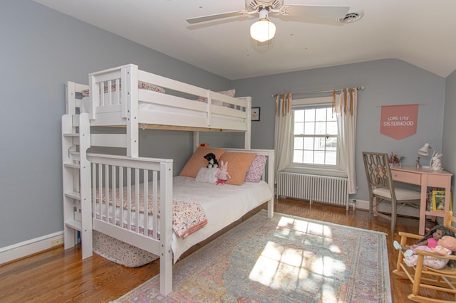 bedroom with radiator, wood finished floors, lofted ceiling, ceiling fan, and baseboards