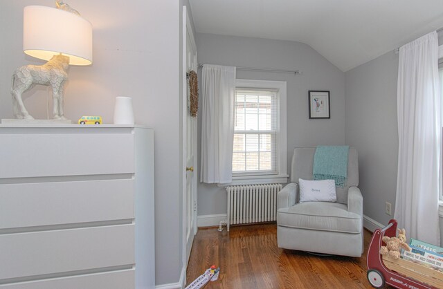 sitting room featuring radiator, wood finished floors, lofted ceiling, and baseboards