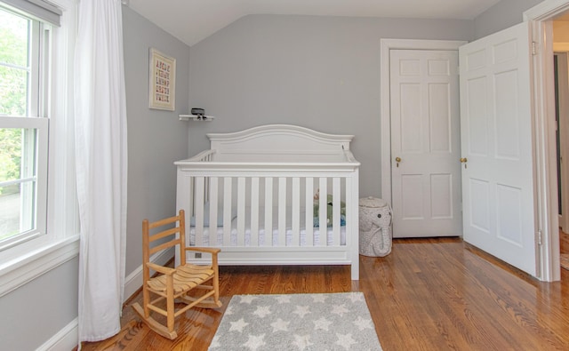 bedroom with vaulted ceiling and wood finished floors