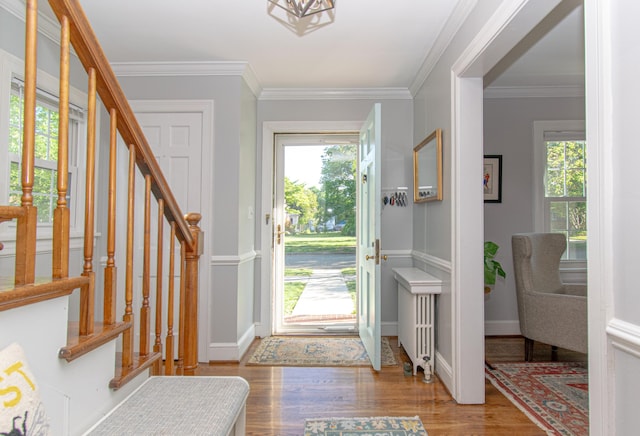 entrance foyer with healthy amount of natural light, wood finished floors, radiator heating unit, stairway, and ornamental molding