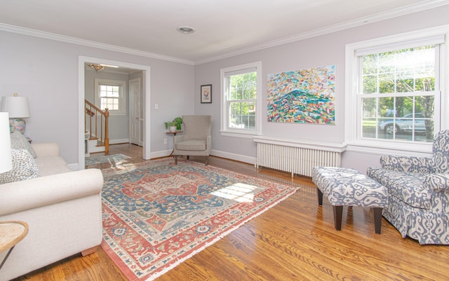 living room with radiator heating unit, stairs, ornamental molding, wood finished floors, and baseboards