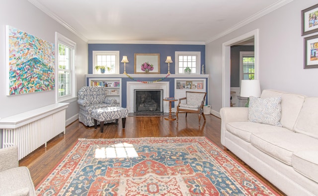 living area with radiator, wood finished floors, a fireplace with flush hearth, ornamental molding, and baseboards