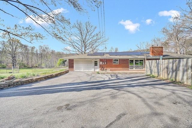 3553 Kidder Ln, Salem, VA 24153 - view of front of house featuring asphalt driveway, a garage, brick siding, roof mounted solar panels, and a chimney