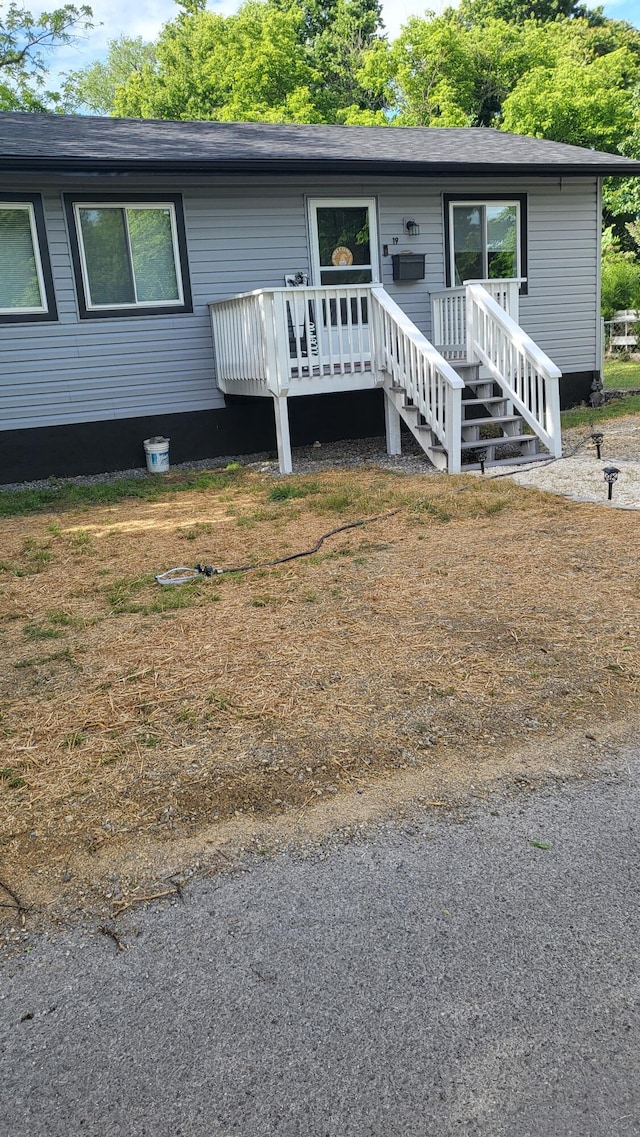 view of front of house featuring a wooden deck and roof with shingles