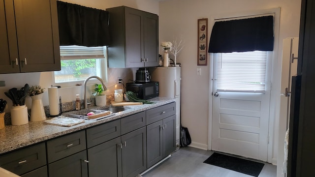 kitchen with black microwave, a sink, light wood-style floors, gray cabinets, and baseboards