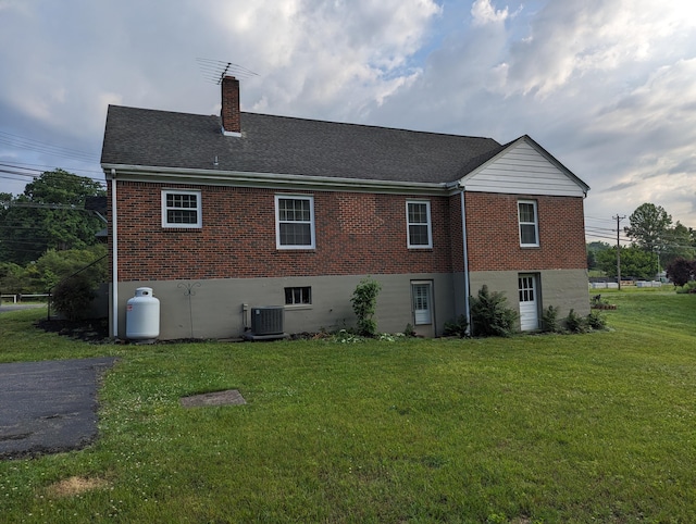 1987 Franklin St, Rocky Mount, VA 24151 - back of property featuring brick siding, a lawn, central AC, a chimney, and roof with shingles